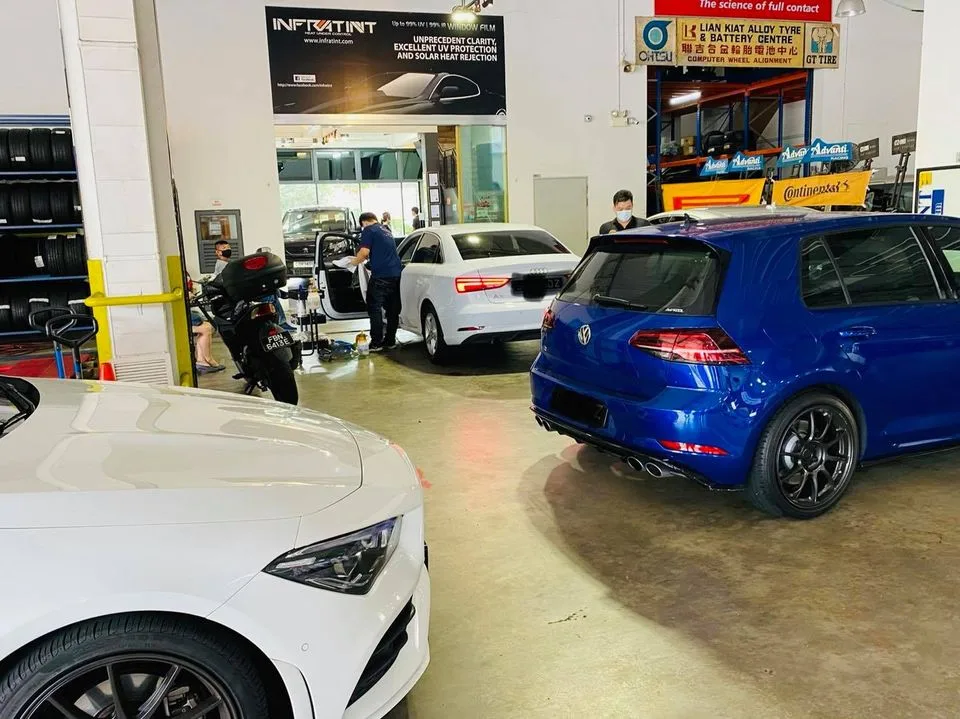 Blue Volkswagen Golf R and white Audi sedan in the workshop at Infratint Singapore
