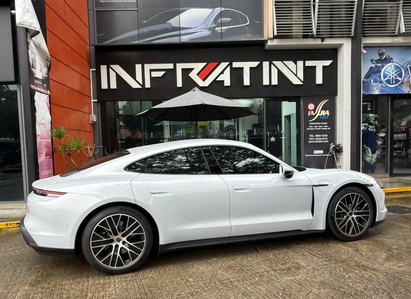 Light grey Porsche Taycan side profile outside Infratint Singapore signage
