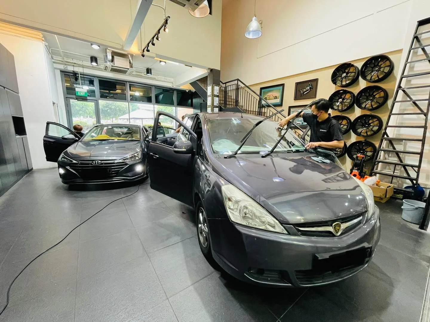 Grey Proton MPV and a grey Toyota wagon inside the Infratint Singapore showroom