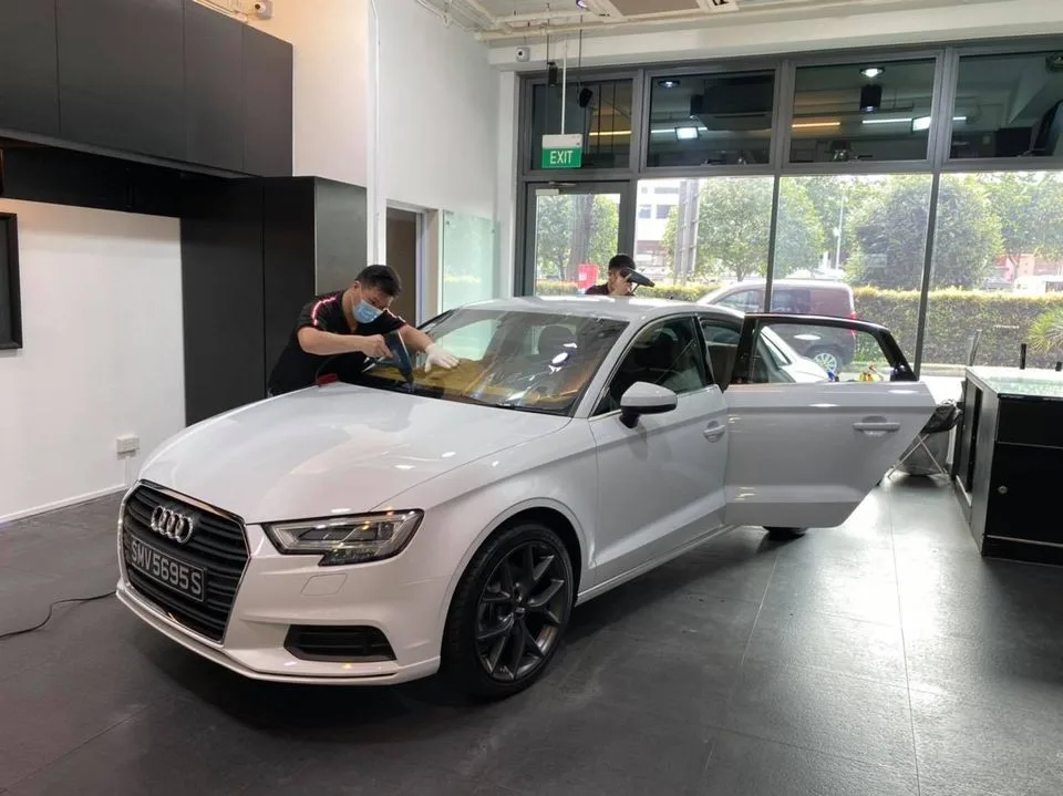 Installers applying window film to a white Audi A3 at Infratint Singapore