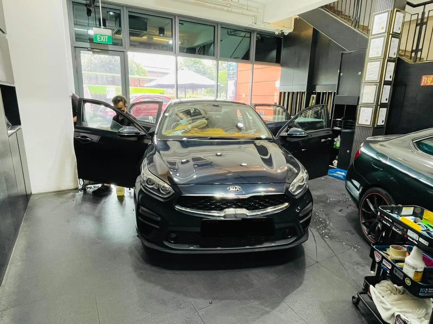 Black Kia sedan getting window film installed at Infratint Singapore