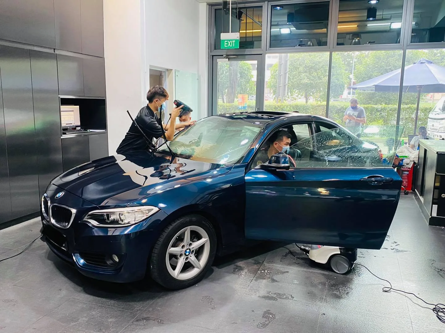 Installer fitting film on a dark blue BMW 2 Series coupe at Infratint Singapore