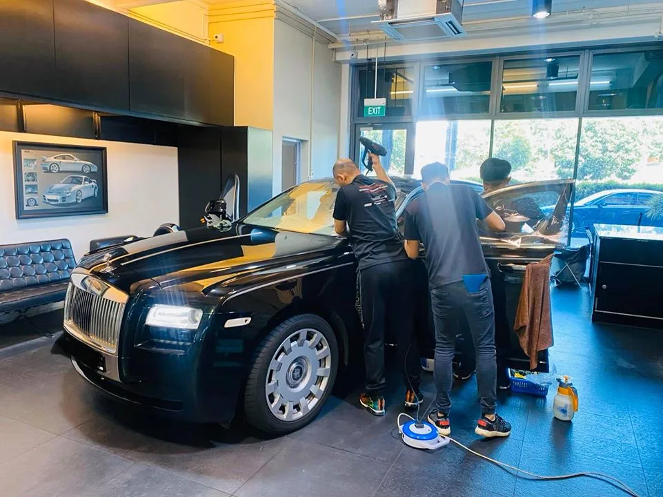 Team fitting window film to a black Rolls-Royce Ghost side glass at Infratint Singapore