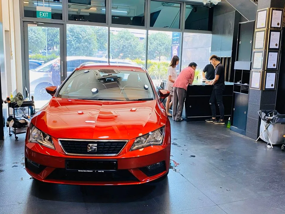 Front view of a red SEAT Leon at Infratint Singapore with certificates on the wall