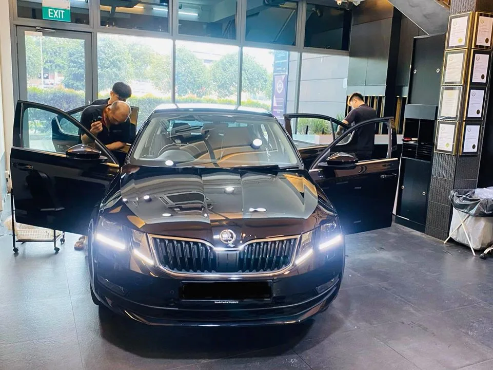 Black Skoda Octavia with doors open during window tinting by installers at Infratint Singapore