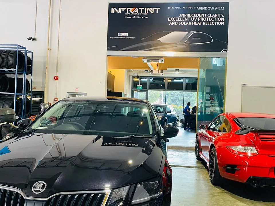 Black Skoda Octavia beside a red Porsche 911 under the Infratint banner at Infratint Singapore