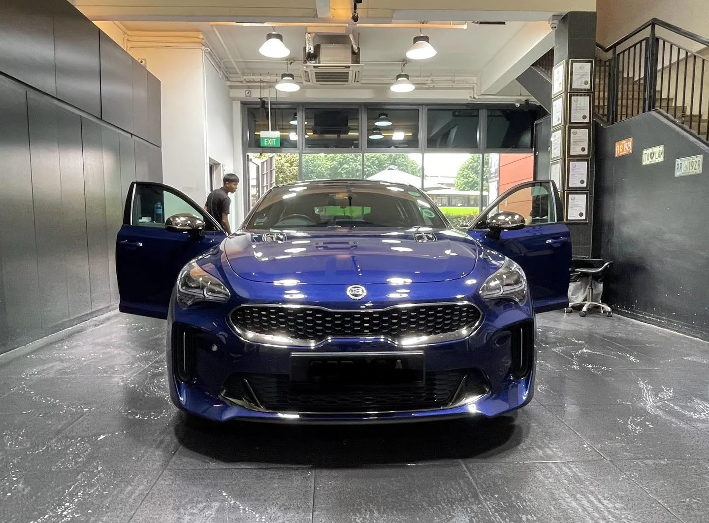 Dark blue Kia Stinger GT with front doors open inside the Infratint workshop Singapore