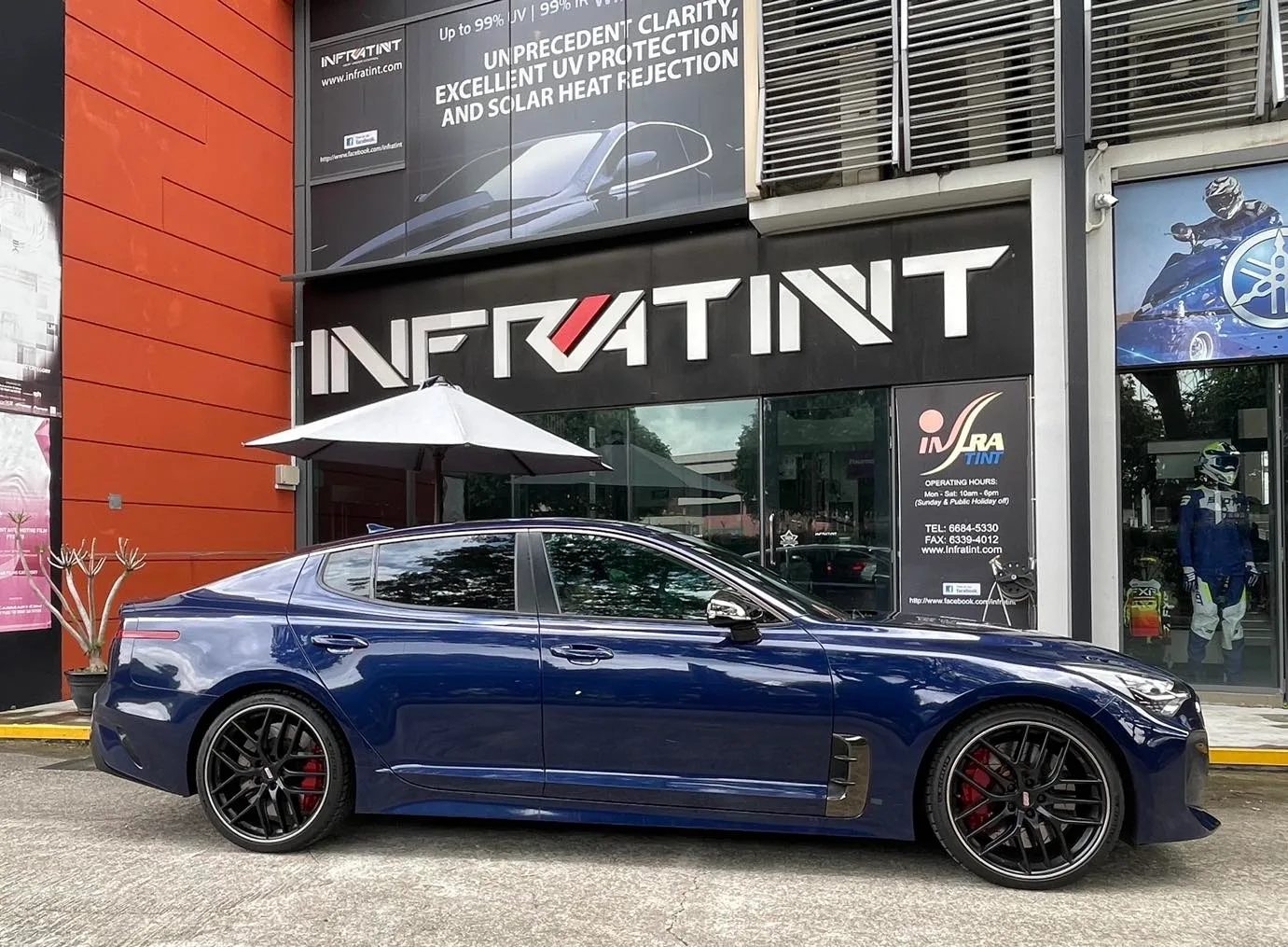 Dark blue Kia Stinger GT side profile with tinted windows outside Infratint Singapore