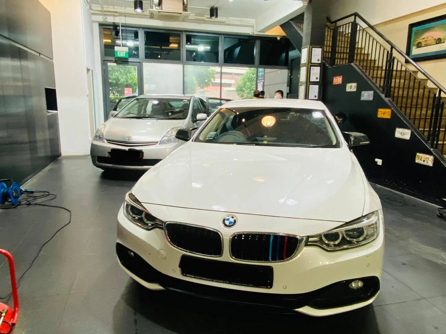 White BMW 4 Series and silver Toyota Prius inside the Infratint Singapore showroom