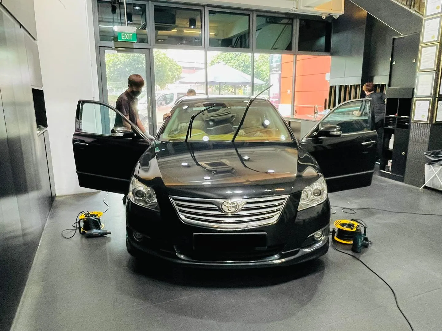 Black Toyota sedan with door open during window film install at Infratint Singapore