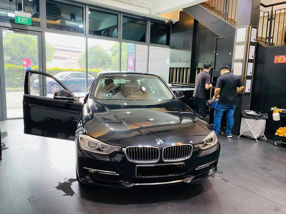 Black BMW 3 Series sedan with technicians preparing film at Infratint Singapore