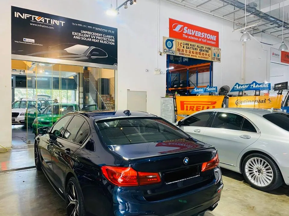 Dark blue BMW sedan and silver Mercedes-Benz waiting for window film at Infratint Singapore