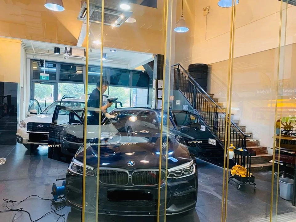 Grey BMW sedan and white Subaru Forester in the glass install bay at Infratint Singapore