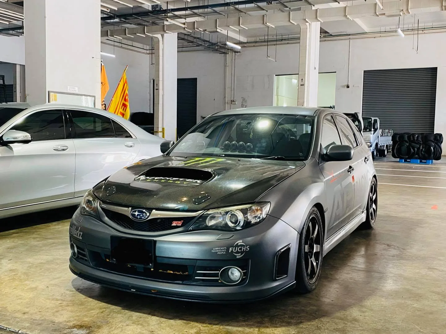 Grey Subaru WRX STI with carbon hood parked in the workshop at Infratint Singapore