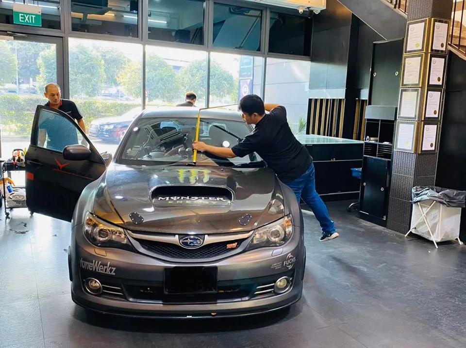 Installer applying window film to a grey Subaru WRX STI at Infratint Singapore