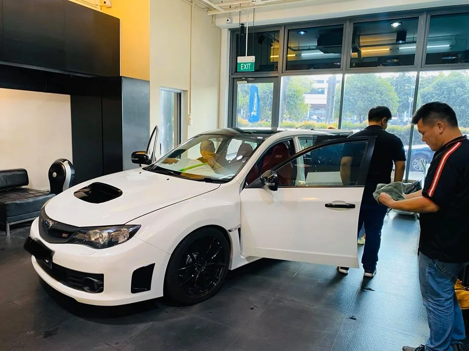 White Subaru WRX STI side profile on black alloys during a tint install at Infratint Singapore