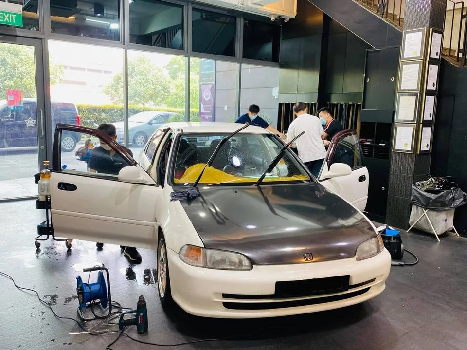 White Honda sedan being tinted by the install team at Infratint Singapore