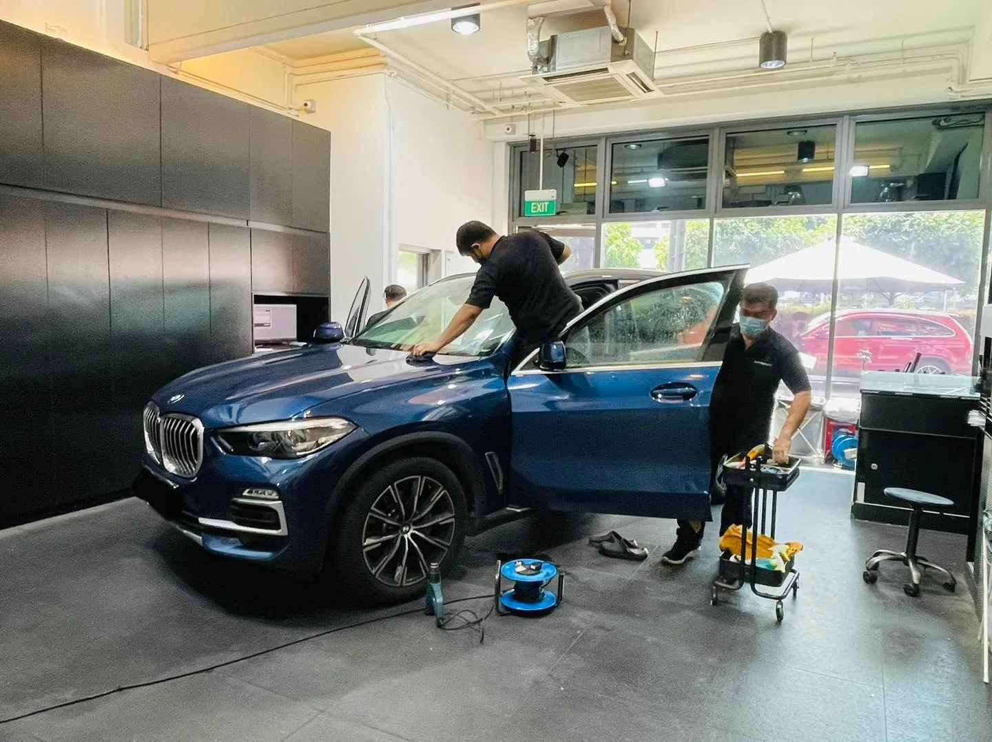Dark blue BMW X5 SUV with door open during window film install at Infratint Singapore