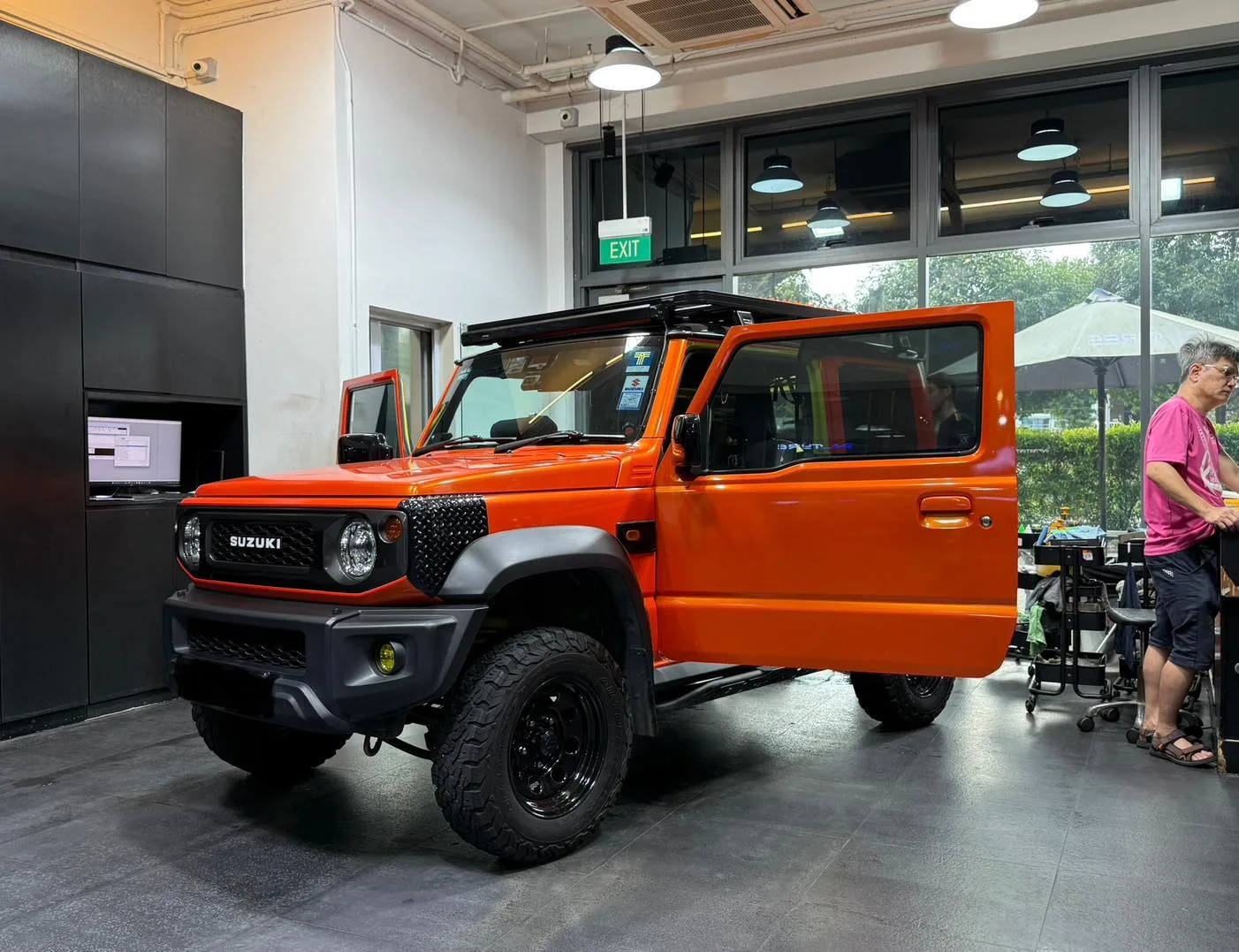 Orange Suzuki Jimny front three-quarter inside the Infratint workshop bay