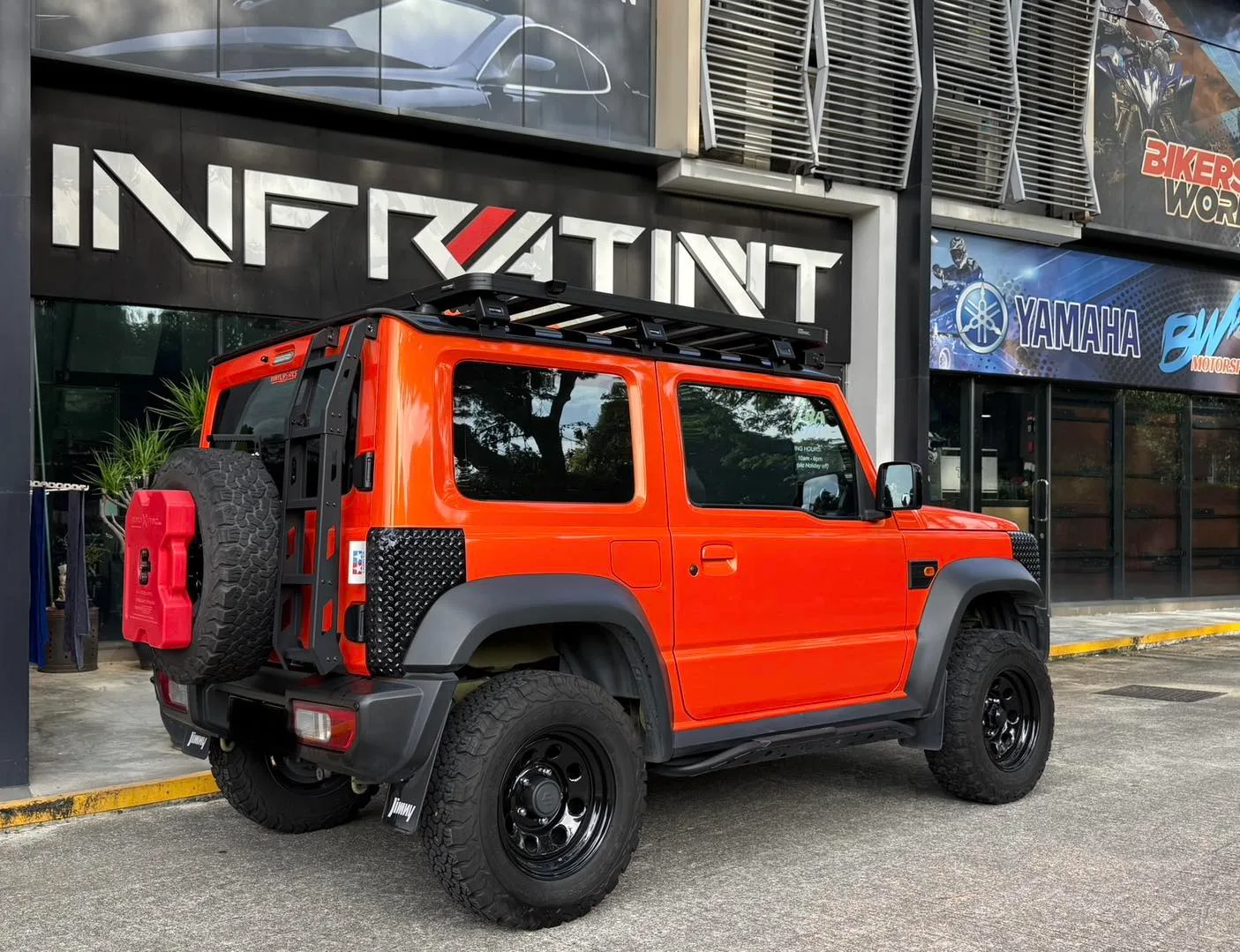 Tinted orange Suzuki Jimny rear three-quarter view with spare wheel at Infratint Singapore