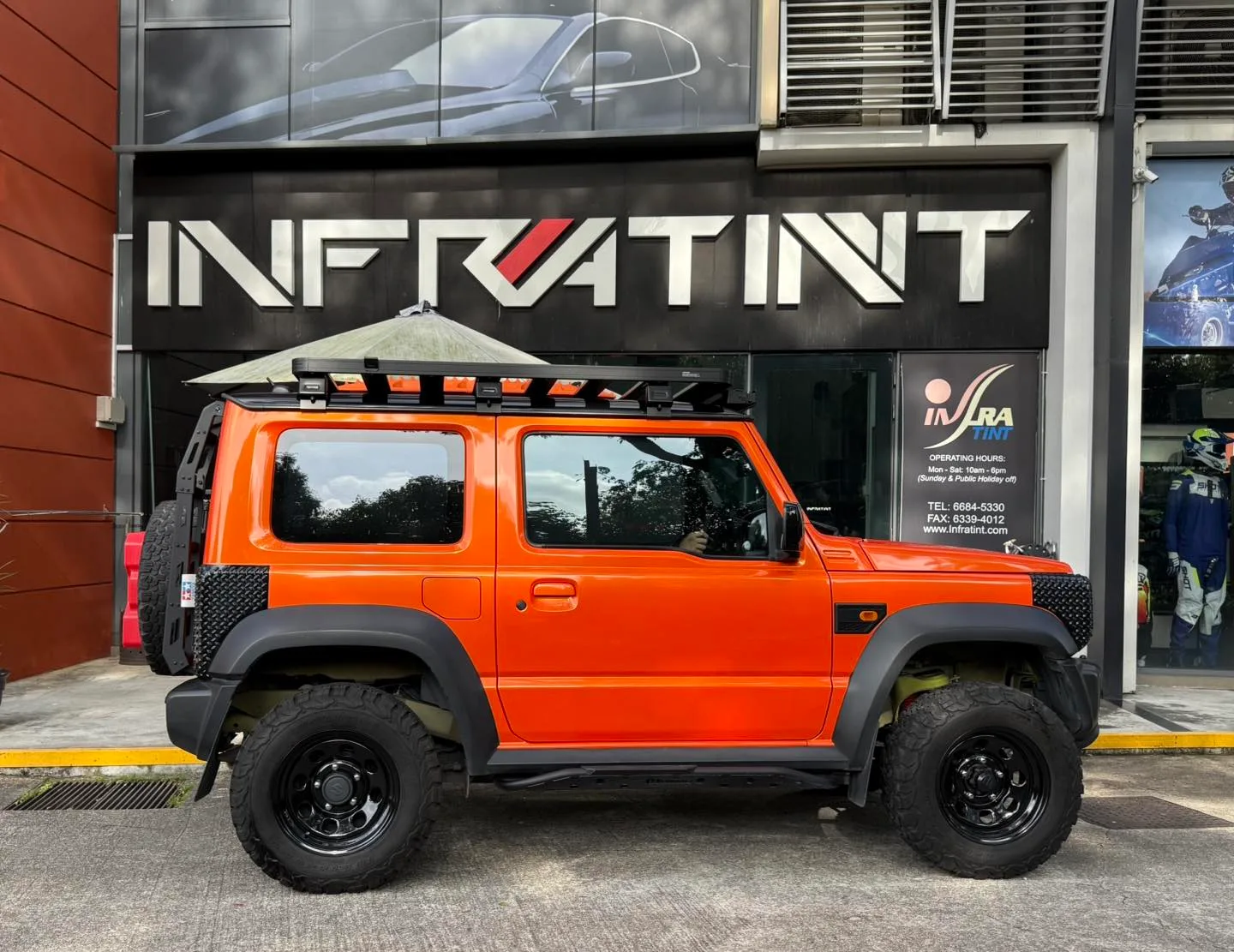Tinted orange Suzuki Jimny side profile outside the Infratint shopfront in Singapore