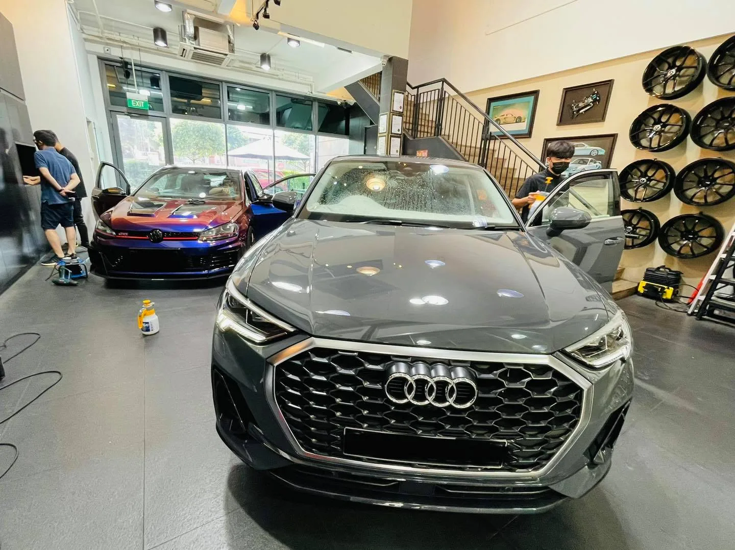 Grey Audi and purple Volkswagen Golf inside Infratint Singapore beside a wheel display