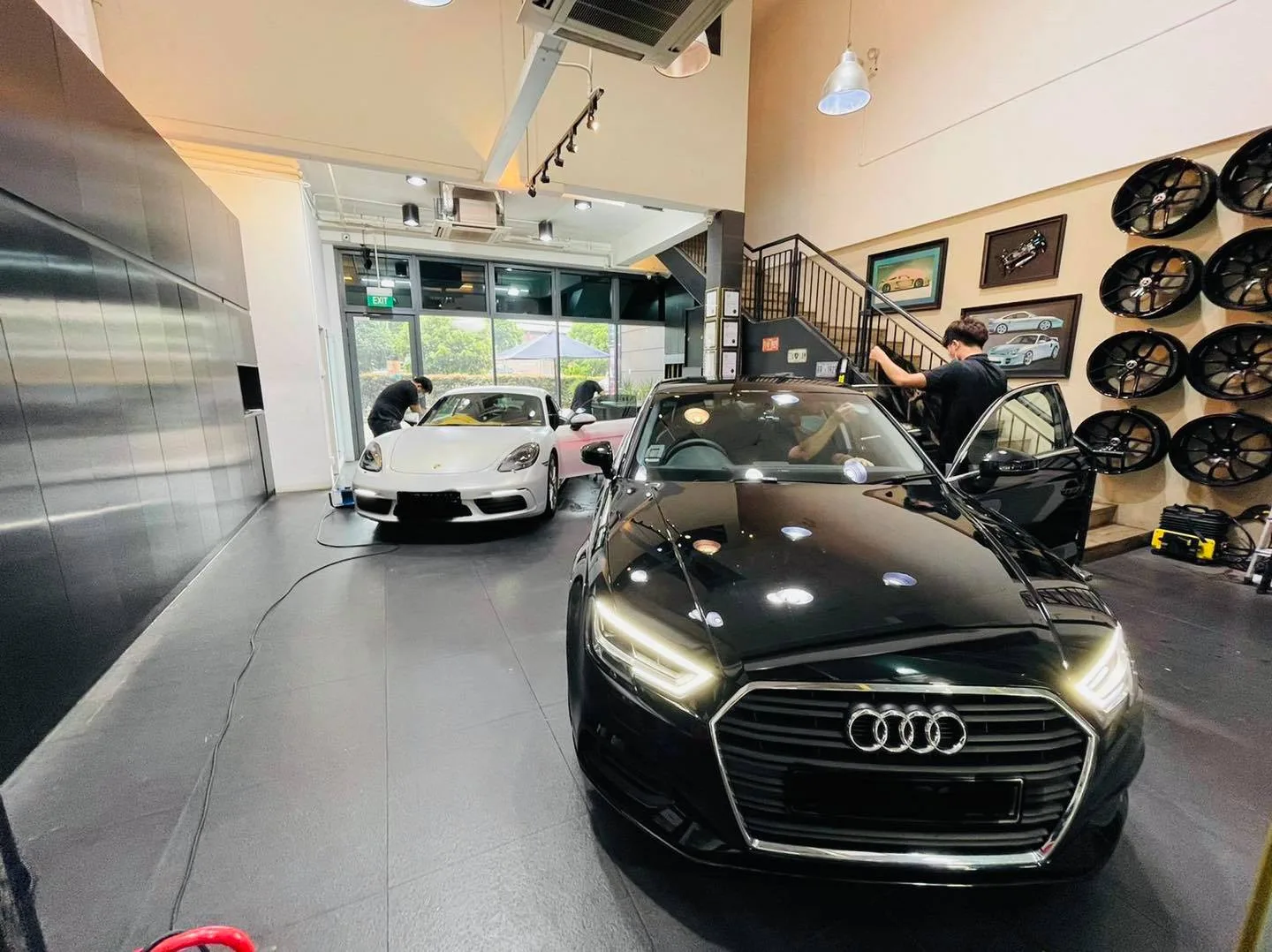 Black Audi sedan and silver sports car inside the Infratint Singapore workshop