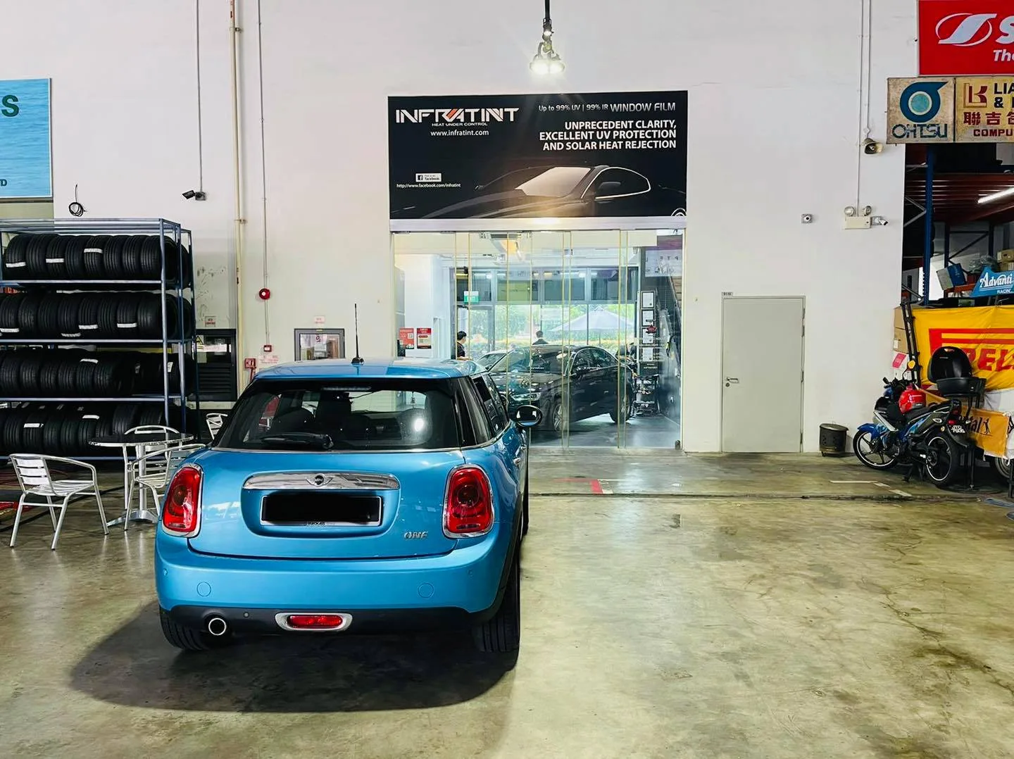 Light blue Mini Cooper rear view beneath the Infratint Singapore banner
