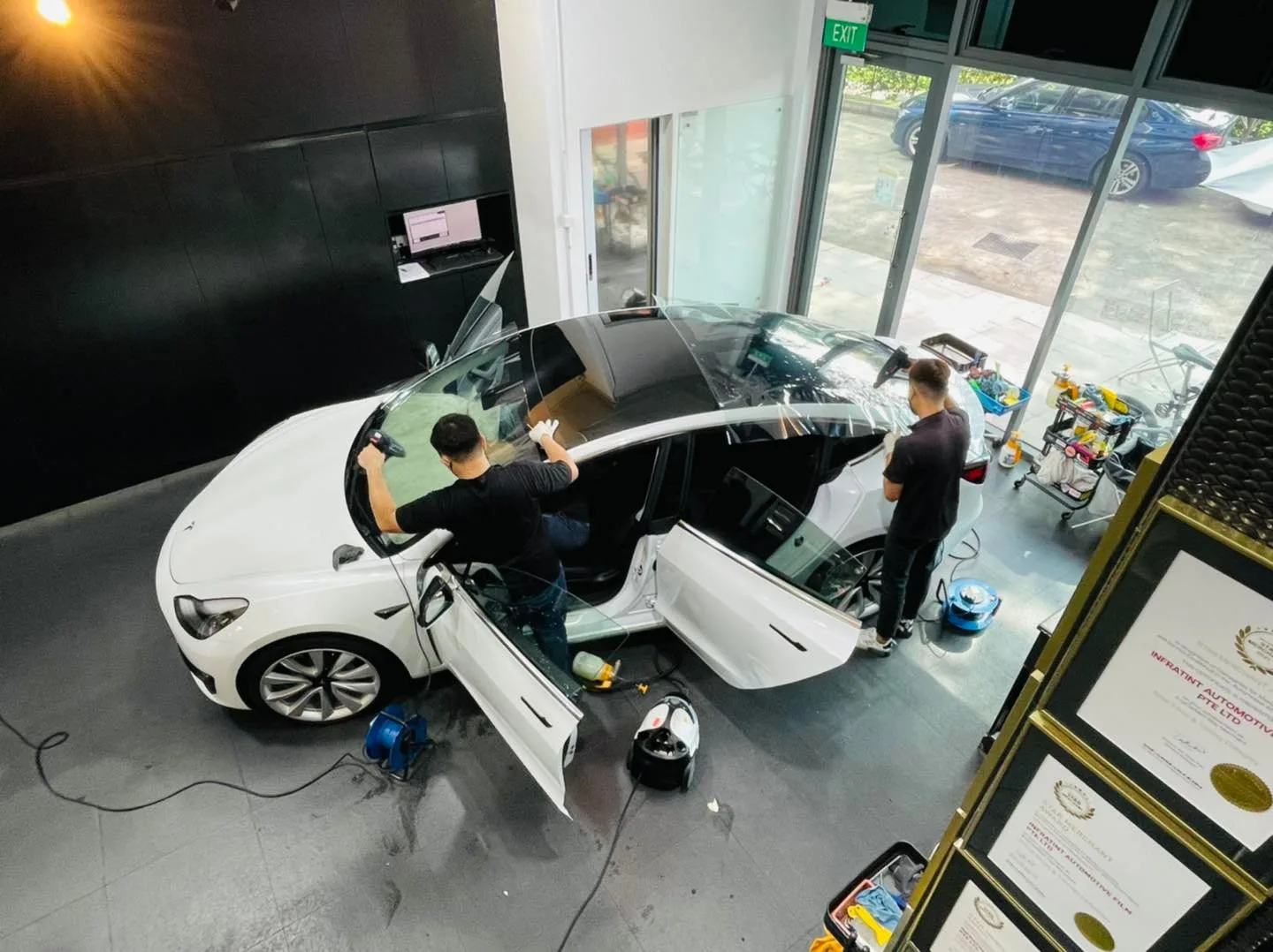 Overhead view of two technicians tinting a white Tesla Model 3 at Infratint Singapore