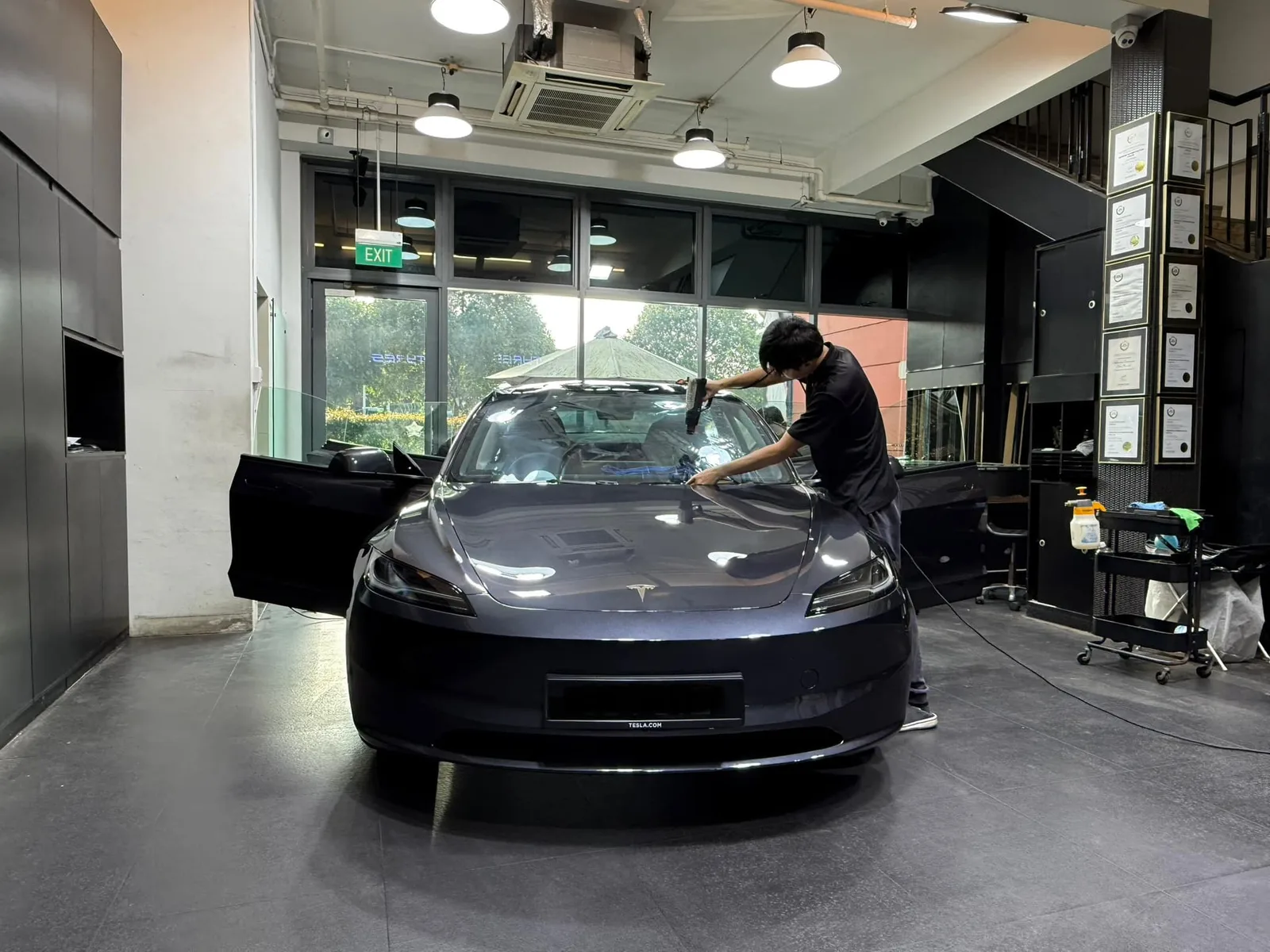Installer applying window film to a Tesla Model 3 Highland windscreen at Infratint Singapore