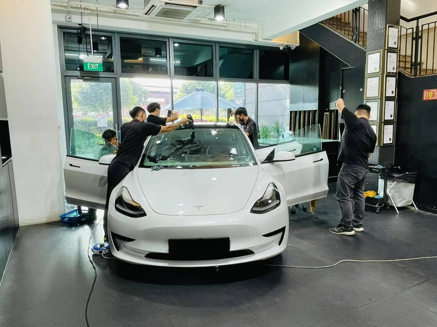 Installers tinting the windscreen of a white Tesla Model 3 at Infratint Singapore