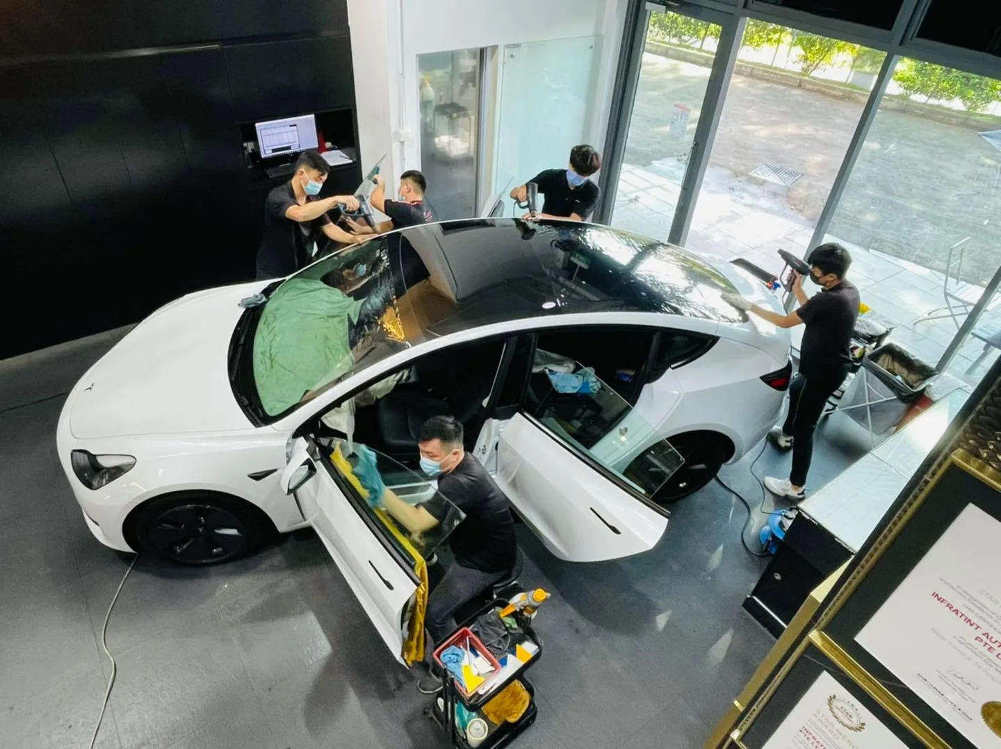 Overhead view of a crew tinting a white Tesla Model 3 at Infratint Singapore