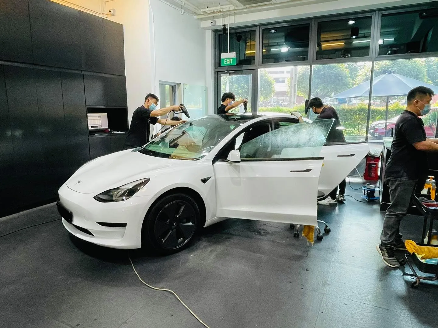 White Tesla Model 3 with doors open during window tinting at Infratint Singapore