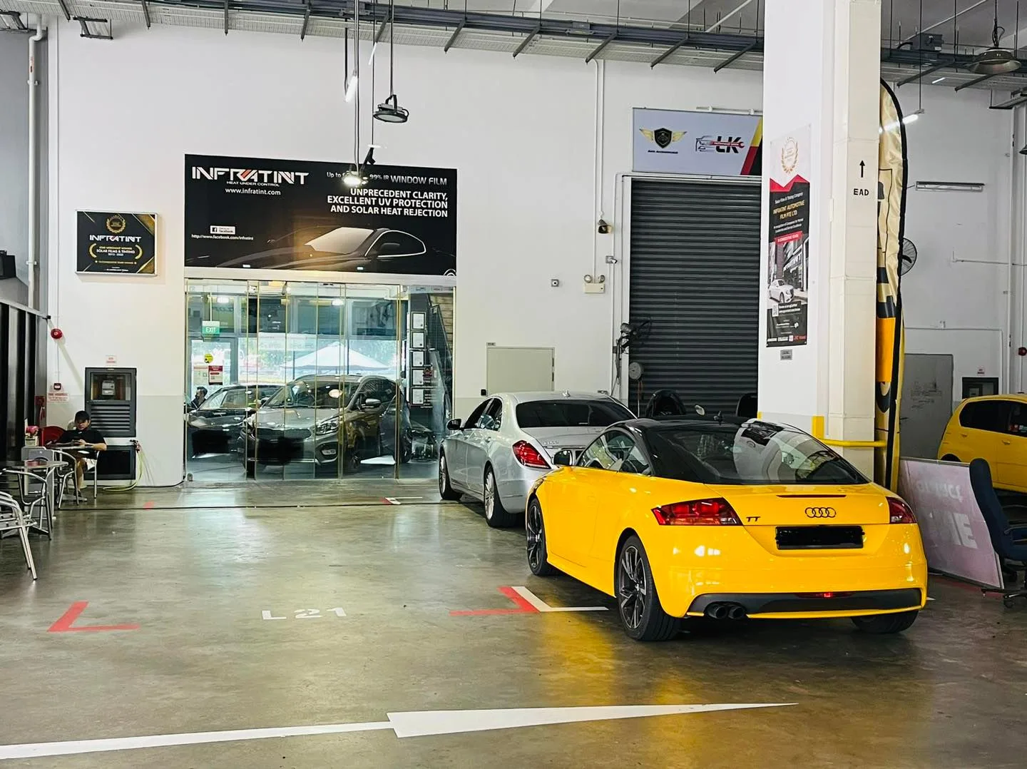 Yellow Audi TT rear view beneath the Infratint Singapore banner in the workshop