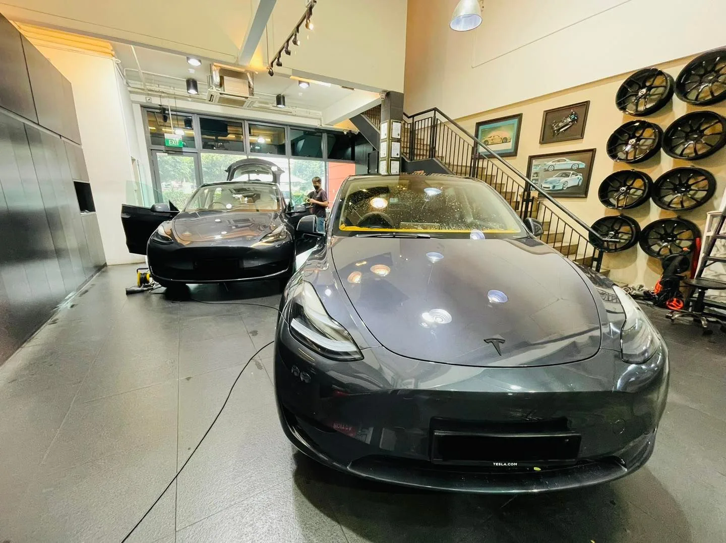 Dark grey Tesla Model 3 in the install bay at Infratint Singapore next to a wheel display