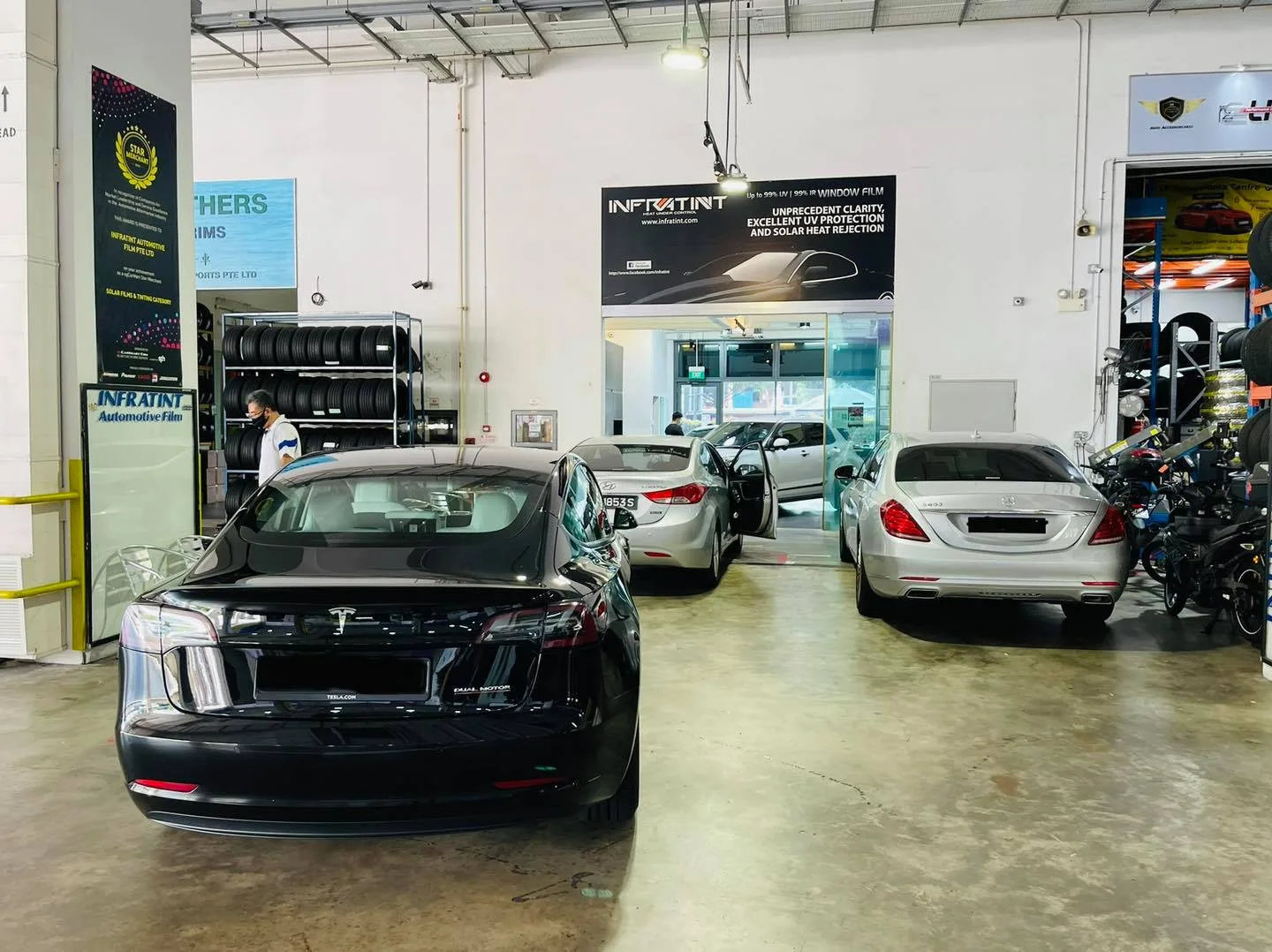 Black Tesla Model 3 and silver Mercedes-Benz sedan inside the Infratint Singapore workshop