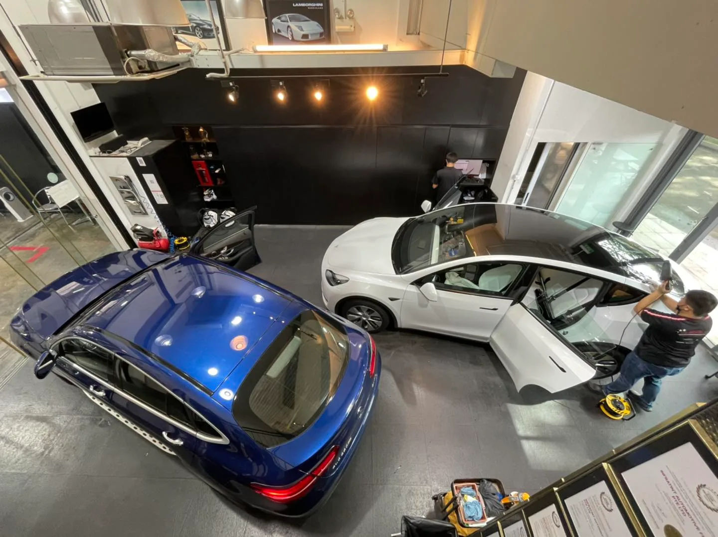Overhead view of a white Tesla Model Y and blue Mercedes during tinting at Infratint Singapore