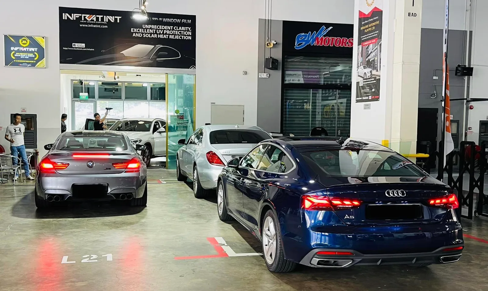 Blue Audi A5 and grey BMW coupe parked at Infratint Singapore window tinting workshop