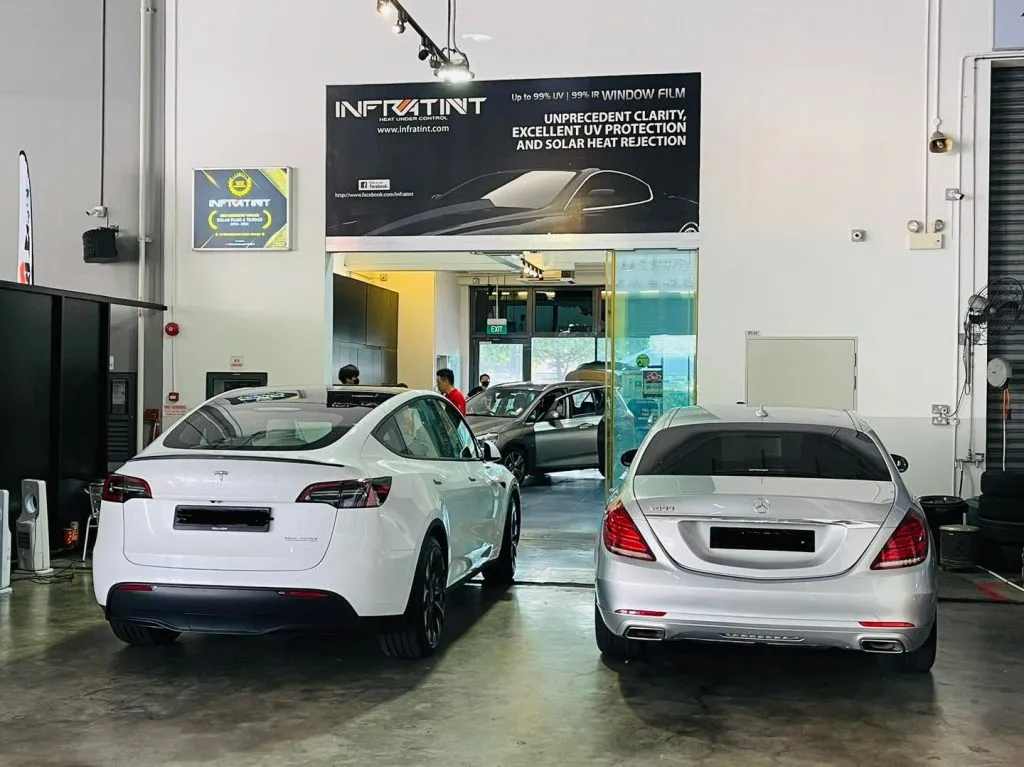 White Tesla Model Y and silver Mercedes-Benz S-Class rear view in the Infratint bay
