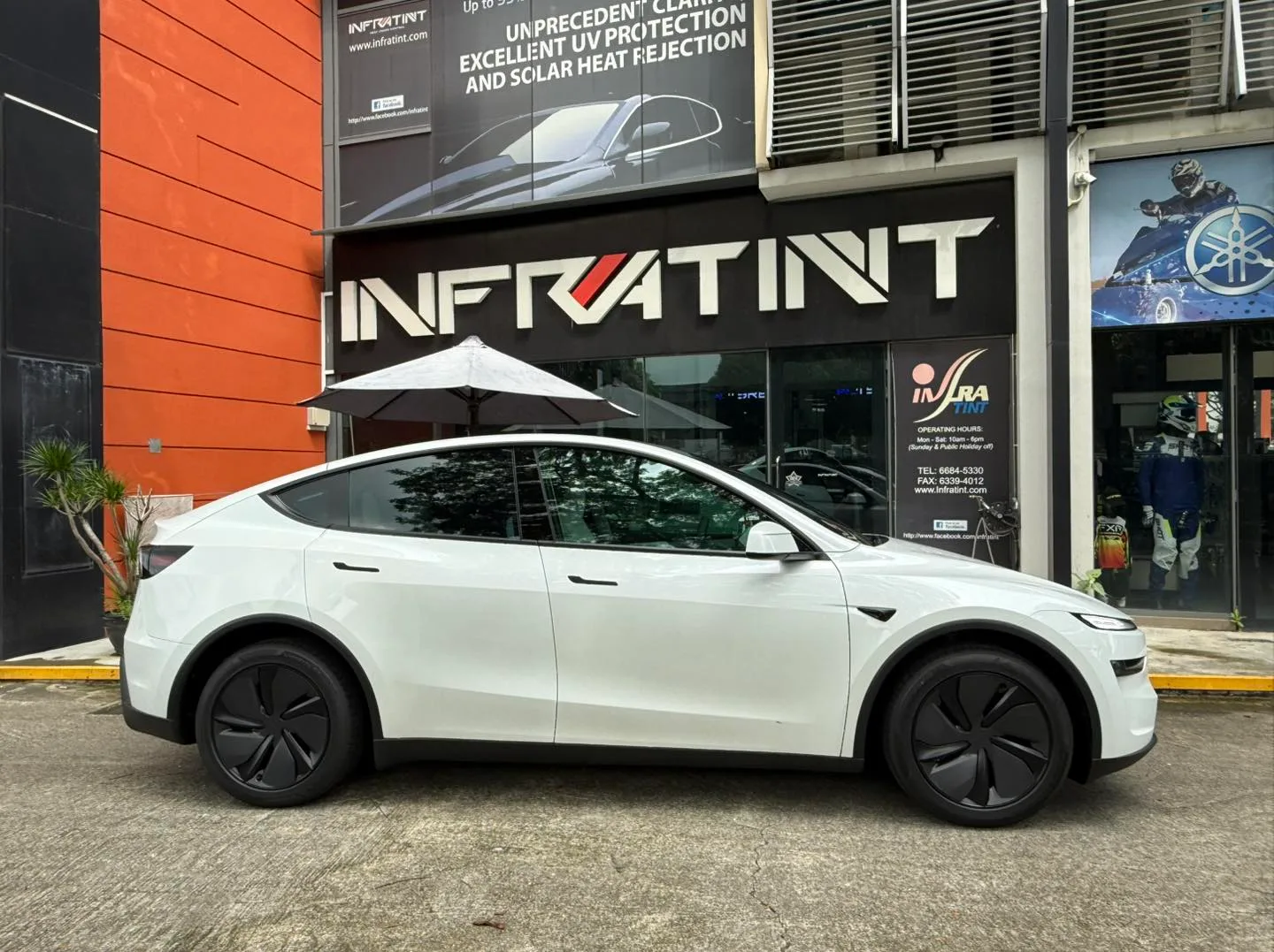 White Tesla Model Y Juniper side profile outside Infratint Singapore signage