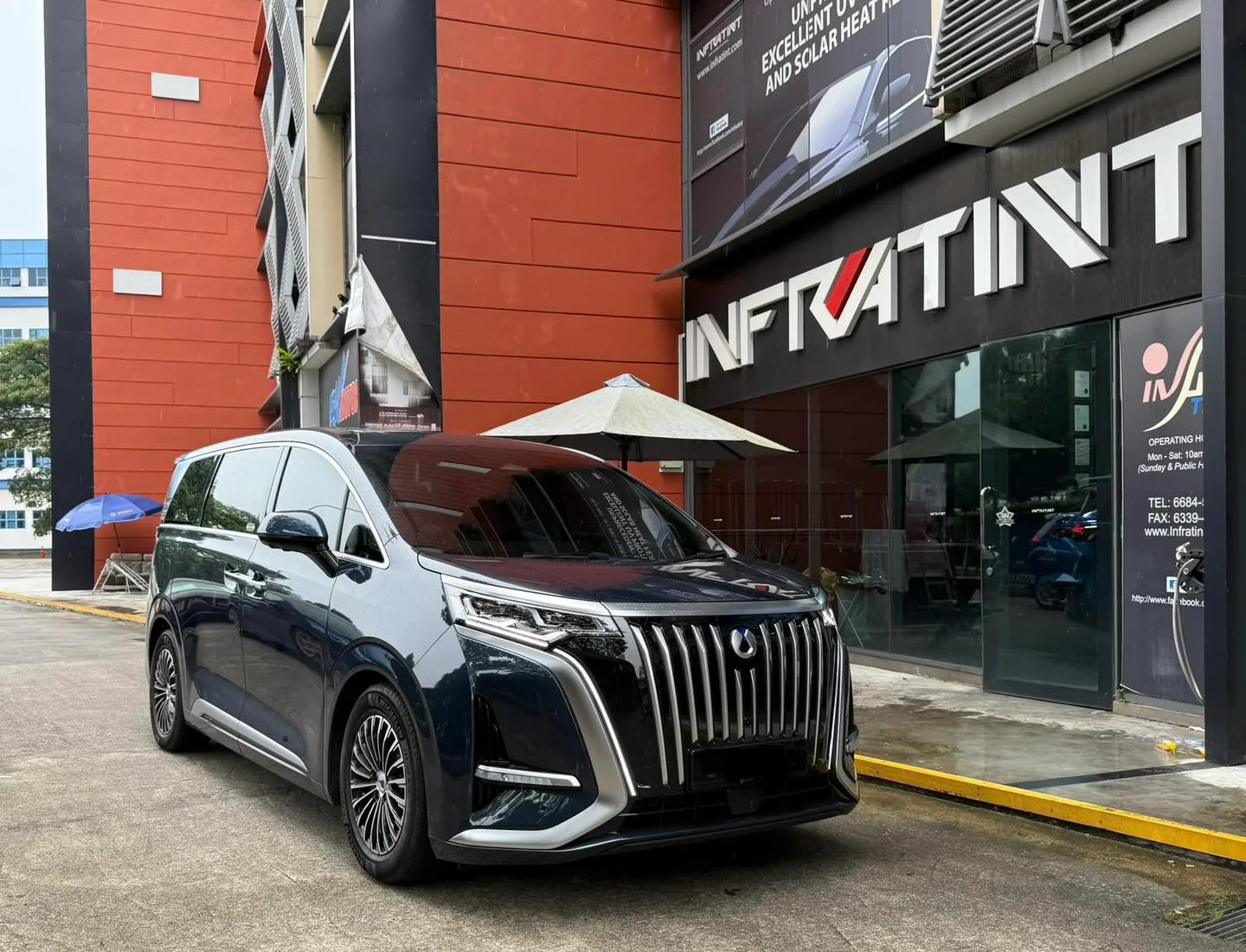 Dark blue Denza luxury MPV front three-quarter view outside Infratint Singapore
