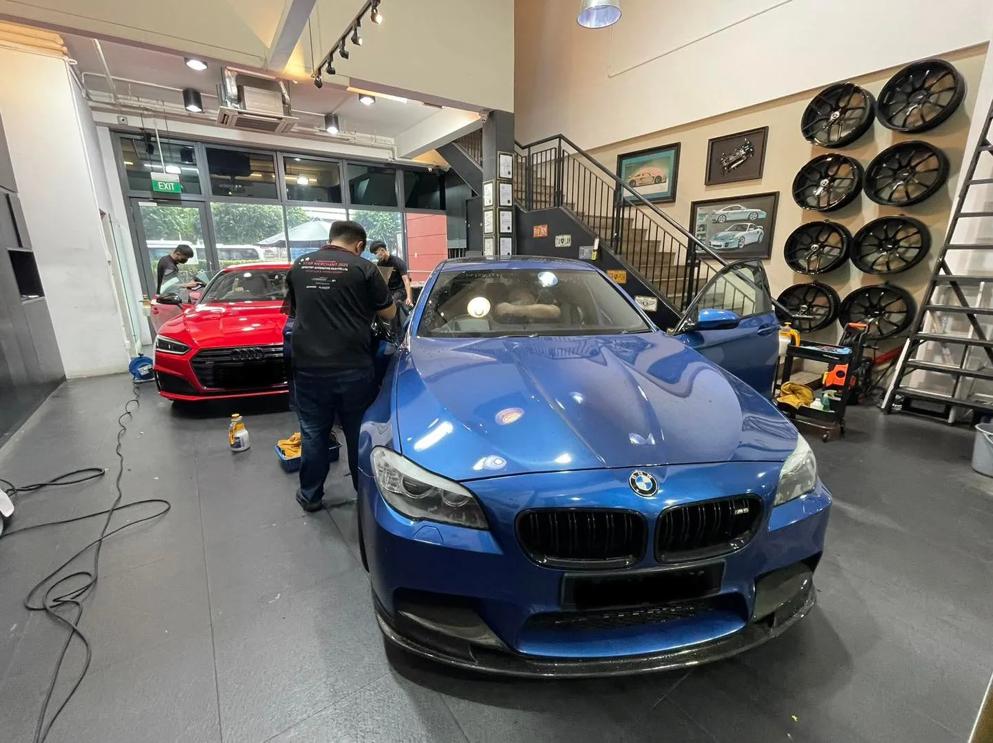Blue BMW 5 Series and red Audi during window film install at Infratint Singapore