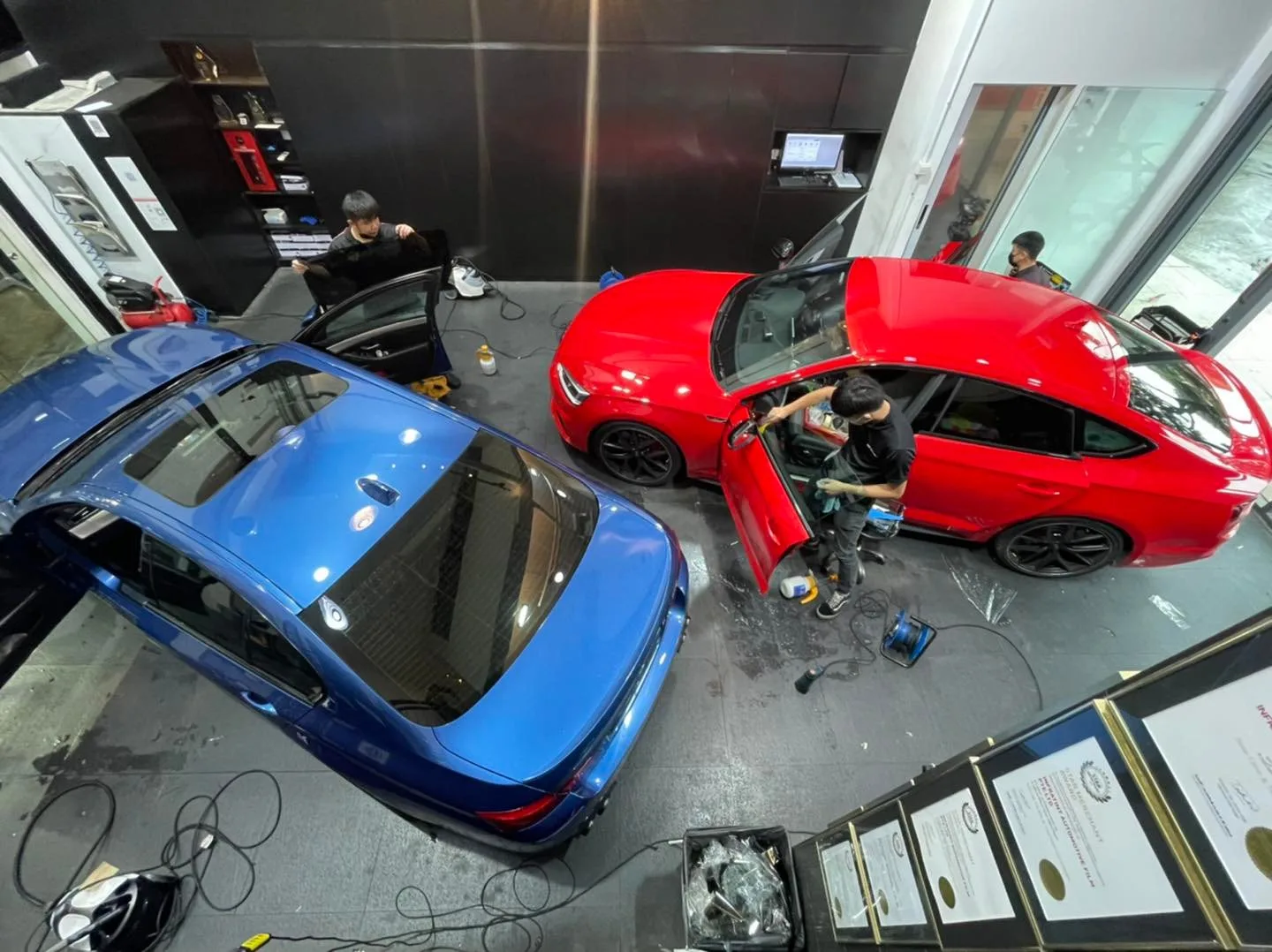 Overhead view of a blue BMW and red Porsche 911 being tinted at Infratint Singapore