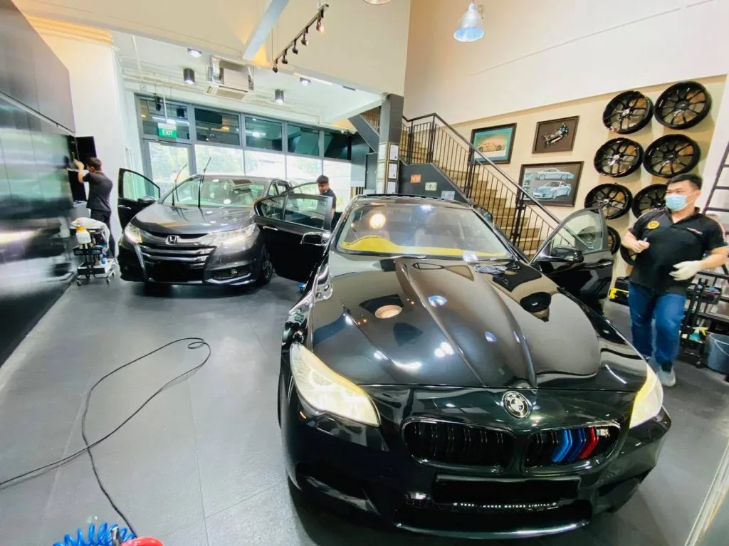 Black BMW 5 Series and grey Honda Odyssey during window film install at Infratint Singapore