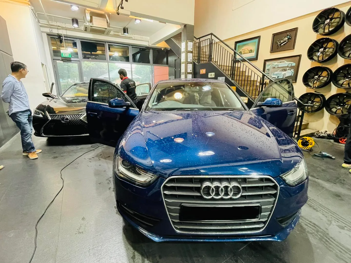 Blue Audi A4 and a black Lexus inside Infratint Singapore beside a wheel display