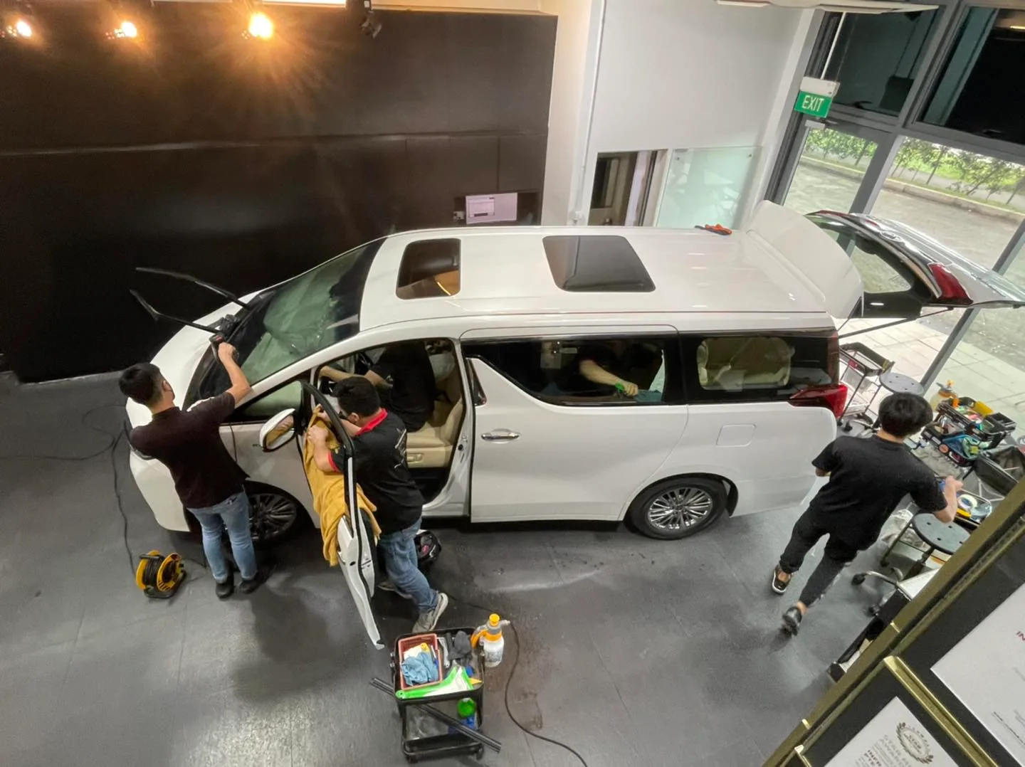 Overhead view of a white Toyota Alphard being tinted by three installers at Infratint Singapore