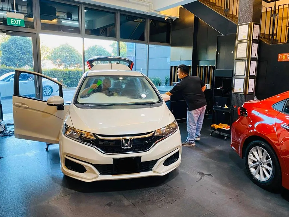 White Honda having its windshield cleaned beside a red Toyota at Infratint Singapore