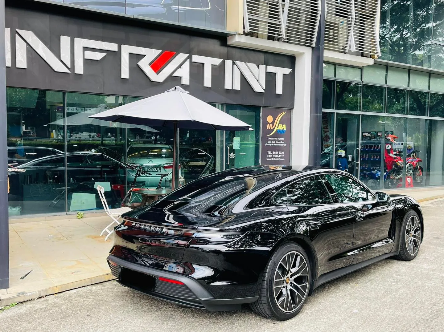 Black Porsche Taycan rear view outside the Infratint Singapore shopfront after window film