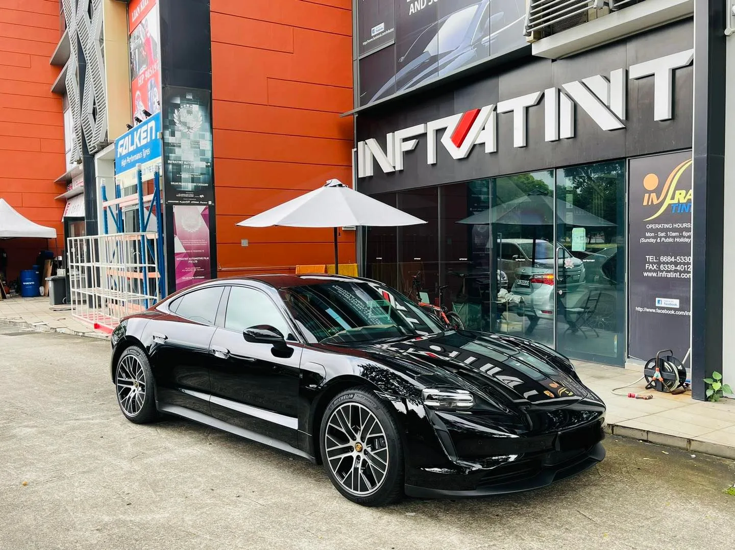 Black Porsche Taycan parked outside the Infratint Singapore shopfront after window tinting