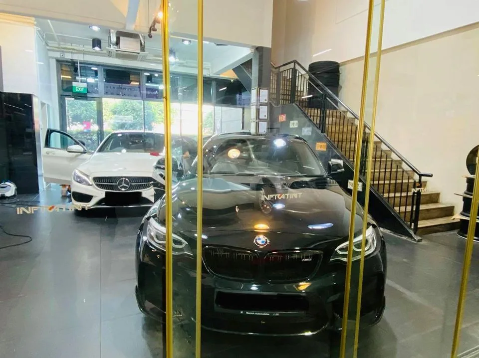 Black BMW coupe and white Mercedes-Benz sedan seen through an Infratint glass partition in Singapore
